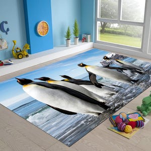 Könnte beinhalten: Ein rechteckiger Teppich mit einem hochauflösenden Fotodruck einer Gruppe von Kaiserpinguinen, die über eine verschneite, eisige Landschaft auf einen blauen Ozean zugehen. Das Design zeigt schwarze, weiße und gelbe Pinguin-Markierungen.