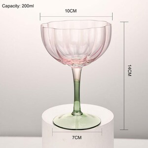 Puede incluir: Un gobelet de vidrio rosa y verde con un dise&ntilde;o acanalado. El gobelet mide 14 cm de alto, 7 cm de ancho y tiene un di&aacute;metro de 10 cm. Capacidad: 200 ml.