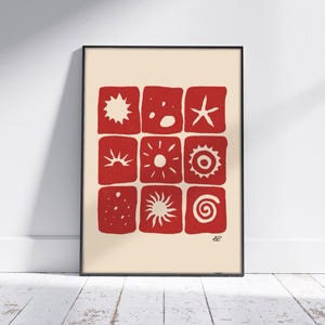 Puede incluir: Una impresión enmarcada con un fondo rojo y formas geométricas blancas. Las formas incluyen estrellas, soles y espirales.