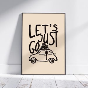 Puede incluir: Impresión artística enmarcada con la frase "LET'S JUST GO" en negro, con un estilo manuscrito. Debajo, un dibujo de un coche con equipaje. El fondo es de color beige claro.