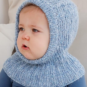 Peut inclure: Une cagoule de bébé en tricot bleu clair. Le capuchon couvre la tête et le cou, avec une ouverture pour le visage. Le bonnet en tricot est fait d'un fil doux et texturé. Le bébé porte un haut bleu.