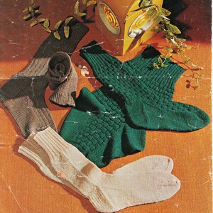May include: Three pairs of knitted socks in different colours and patterns. One pair is brown, one is green, and one is white.