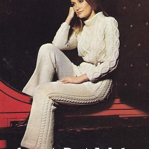 Peut inclure: Ensemble en tricot crème composé d'un pull à col roulé et d'un pantalon assorti. Le pull présente des détails en tricot torsadé sur les manches et le corsage. Le pantalon a une jambe évasée et un motif en tricot torsadé le long des coutures latérales. L'ensemble est en fil doux et texturé.