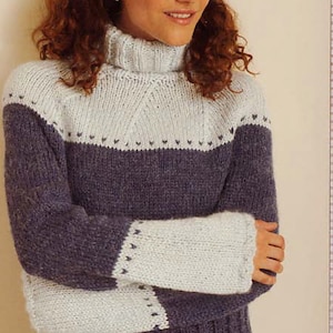 Könnte beinhalten: Ein blauer und weißer Strickpullover mit Rollkragen und geometrischem Muster. Der Pullover ist aus weichem, flauschigem Garn gefertigt.