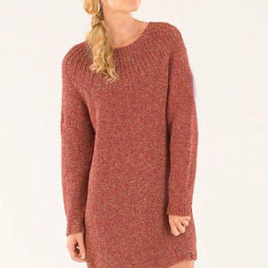 Op de afbeelding: Een lange, roestkleurige trui-jurk met lange mouwen en een textuurrijk gebreid patroon. De trui heeft een ronde hals en een licht aansluitende pasvorm.