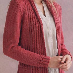 Op de afbeelding: Een lange, open cardigan in een gedempte rode tint. Het breiwerk heeft een geribbeld ontwerp op de voorpanelen en mouwen, met een gladde breiwerk op de rug. De cardigan heeft lange mouwen en een sjaalkraag.