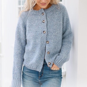 May include: A pale blue cardigan with a round neck and long sleeves. It features a button-up front with five brown buttons. The model is wearing blue jeans. The sweater is made of a soft, textured knit, suitable for cooler weather.