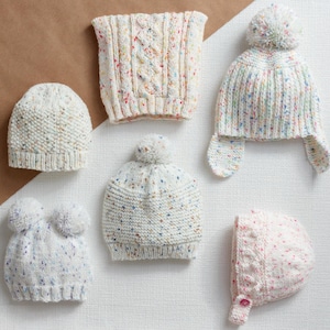 Könnte beinhalten: Eine Auswahl an handgestrickten Mützen und einem Schal in Weiß und Creme mit bunten Sprenkeln. Stile umfassen eine Beanie, eine Mütze mit Ohrenklappen und eine Mütze mit Bommel. Der Schal hat ein Zopfmuster.