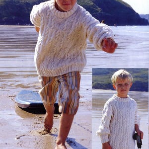 May include: A young person wearing a cream-colored cable-knit sweater and striped shorts, running on a sandy beach. The sweater has a round neck and long sleeves. A small image of the same person is in the lower right corner.