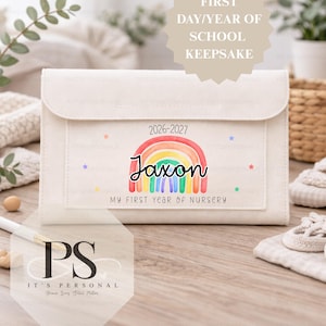 May include: Off-white keepsake pouch featuring a rainbow design and the name "Jaxon." The pouch has a flap closure and a front pocket. Text on the pouch reads "2026-2027" and "My First Year of Nursery."