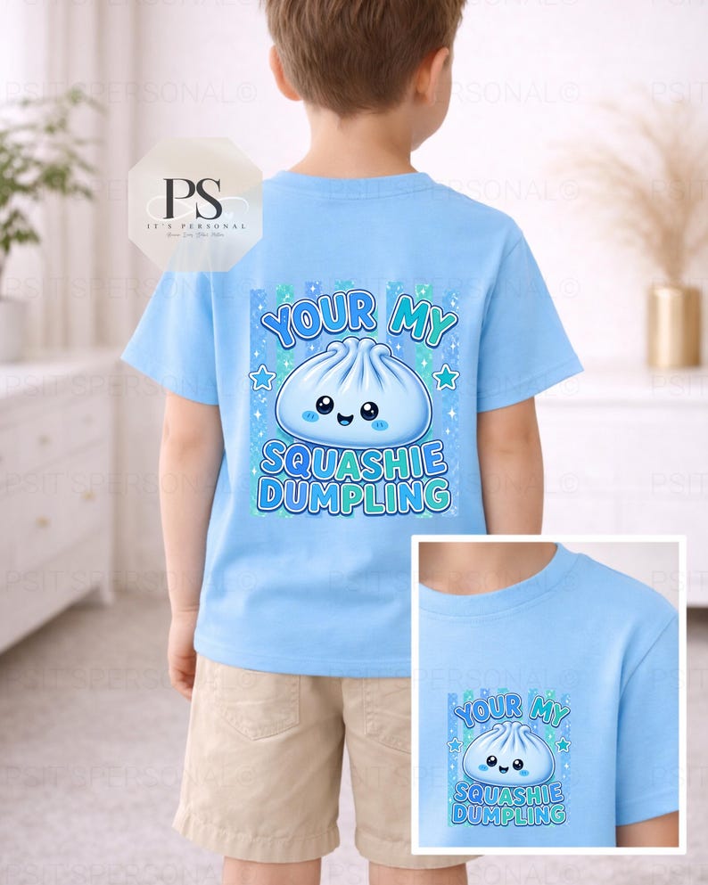 May include: A light blue t-shirt with a cartoon dumpling design and the text "YOUR MY SQUASHIE DUMPLING". The shirt is worn by a child. The design includes blue stars and a cute dumpling illustration.