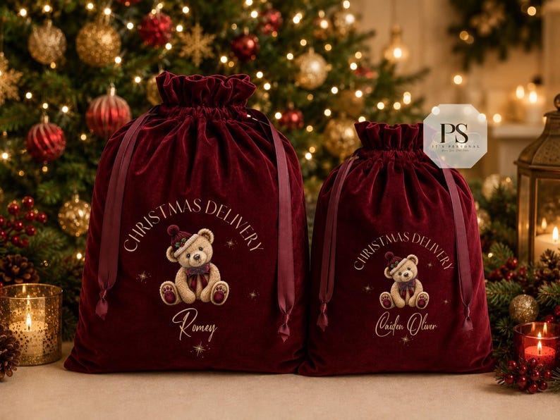 May include: Two deep red velvet drawstring bags featuring a graphic of a teddy bear wearing a hat and scarf. The text CHRISTMAS DELIVERY is printed above the bear, with the names Romey and Caiden Oliver printed below in a script font.