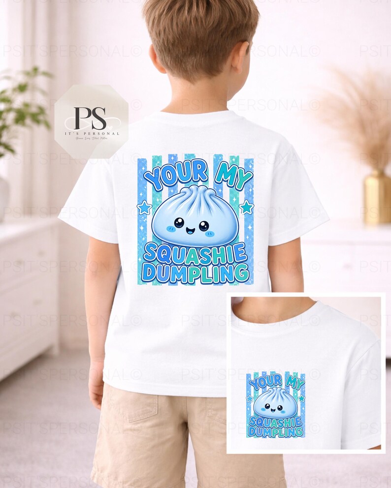 May include: White t-shirt with a blue dumpling graphic and the text "YOUR MY SQUASHIE DUMPLING". The design includes blue stripes and stars. The shirt is worn by a child.