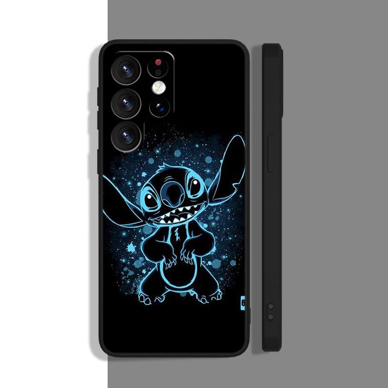 Peut inclure: Coque de t&eacute;l&eacute;phone noire avec un personnage de dessin anim&eacute; bleu et noir sur un fond de galaxie noir et blanc. Le personnage a une grosse t&ecirc;te avec deux grandes oreilles et un large sourire. La coque de t&eacute;l&eacute;phone a une d&eacute;coupe pour l'appareil photo avec trois objectifs.