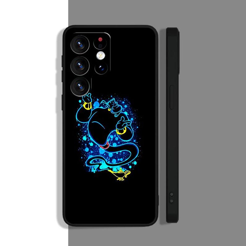 Peut inclure: Une coque de t&eacute;l&eacute;phone noire avec un graphique bleu et jaune d'un g&eacute;nie d'Aladdin. Le g&eacute;nie est dans une pose comme s'il volait. La coque de t&eacute;l&eacute;phone a un bo&icirc;tier d'appareil photo noir avec trois objectifs.