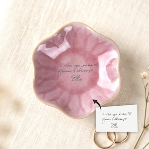 May include: A pink, petal-shaped trinket dish with a glossy finish. The dish has a handwritten inscription that reads "I love you more forever & always Ellie". Two gold rings and a small card with the same inscription are also visible.