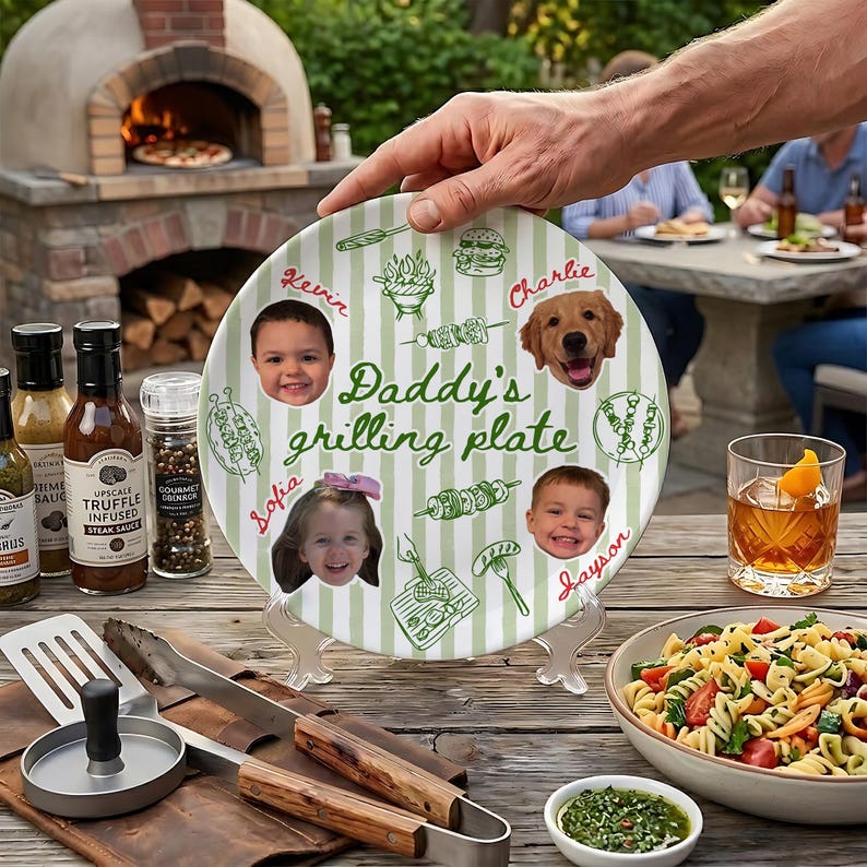 May include: A round ceramic plate with a light green and white striped pattern, featuring the text "Daddy's grilling plate" in green script. The plate includes printed photos of two children and a dog, alongside green line drawings of grill food.