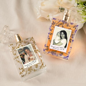 May include: Two clear perfume bottles with gold floral designs and photos of a mother and child. The bottles have the text "Forever your little girl I love you mom."