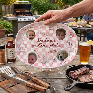 May include: An oval ceramic plate with a pink and white checkered pattern, featuring the text "Daddy's grilling plate" in the center. The plate includes three circular photo portraits of children, one photo of a golden retriever, and illustrations of grilling tools, food, and names.