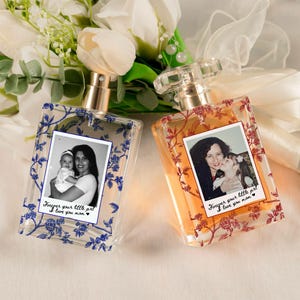 May include: Two rectangular perfume bottles with photos and floral designs. One bottle has blue floral accents and a photo of a woman and baby. The other has red floral accents and a photo of a woman and child. Text reads "Forever your little girl I love you mom."