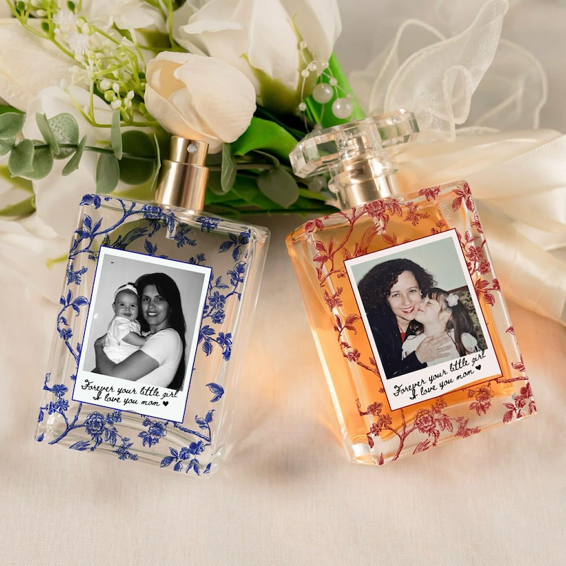 May include: Two rectangular perfume bottles with photos and floral designs. One bottle has blue floral accents and a photo of a woman and baby. The other has red floral accents and a photo of a woman and child. Text reads "Forever your little girl I love you mom."