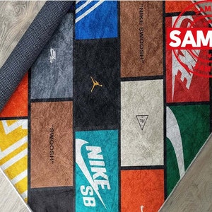 Puede incluir: Una alfombra colorida con un dise&ntilde;o de patchwork que presenta varios logotipos de Nike, incluyendo el Swoosh, Jumpman y SB. La alfombra est&aacute; hecha de un material suave y duradero y es perfecta para agregar un toque de estilo a cualquier habitaci&oacute;n.