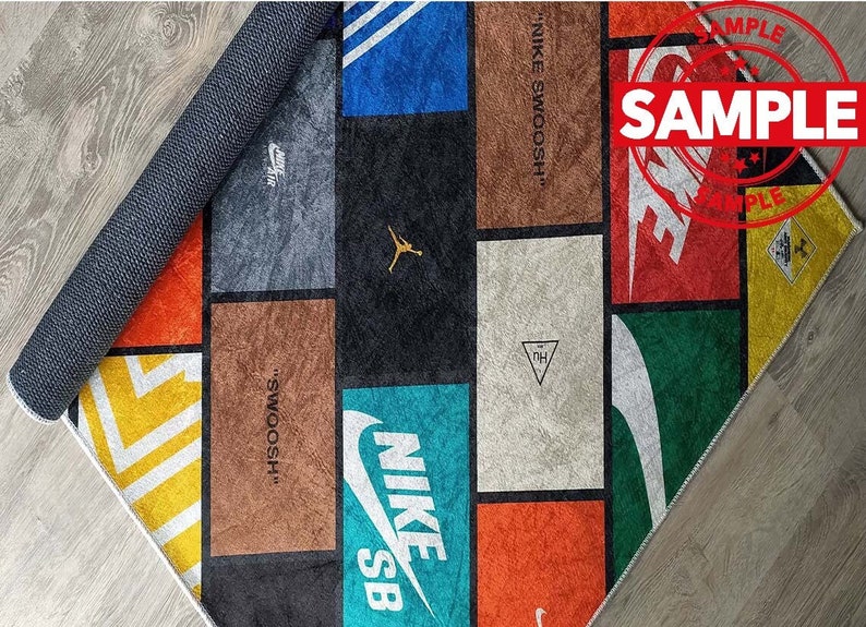 Puede incluir: Una alfombra colorida con un dise&ntilde;o de patchwork que presenta varios logotipos de Nike, incluyendo el Swoosh, Jumpman y SB. La alfombra est&aacute; hecha de un material suave y duradero y es perfecta para agregar un toque de estilo a cualquier habitaci&oacute;n.