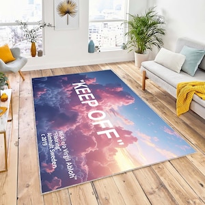 Può includere: Un tappeto rosa e blu con un design a nuvole bianche e il testo "KEEP OFF" in bianco. Il testo "IKEA c/o Virgil Abloh™" è anche stampato sul tappeto, insieme a "Flooring", "Almhult Sweden" e "c 2019".