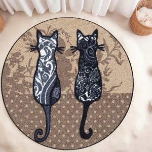 Könnte beinhalten: Eine runde braune und beige Fußmatte mit zwei schwarzen und weißen Katzen mit Blumenmustern. Die Katzen schauen sich an und haben ihre Schwänze eingerollt.