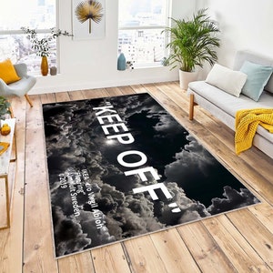 Può includere: Tappeto nero e bianco con un motivo a nuvole e il testo "KEEP OFF" in bianco. Il testo "IKEA®/Virgil Abloh™ Flooring" è anche visibile in bianco.