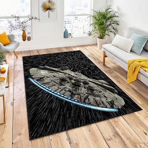 Puede incluir: Una alfombra negra y blanca con un estampado gráfico de la nave espacial Millennium Falcon de Star Wars. La nave espacial vuela a través de un campo de estrellas.