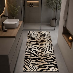 Op de afbeelding: Een rechthoekige badmat met een zebraprint in zwart en beige. De mat ligt op een lichtgrijze tegelvloer in een badkamer. Het ontwerp van de mat voegt een gedurfd, dierenprint accent toe aan de ruimte.