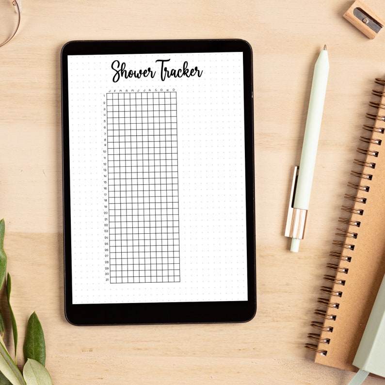 Puede incluir: Una tableta digital que muestra un rastreador de duchas en blanco y negro con una cuadr&iacute;cula y el texto "Shower Tracker" en la parte superior. Los meses del a&ntilde;o est&aacute;n listados en la parte superior de la cuadr&iacute;cula.