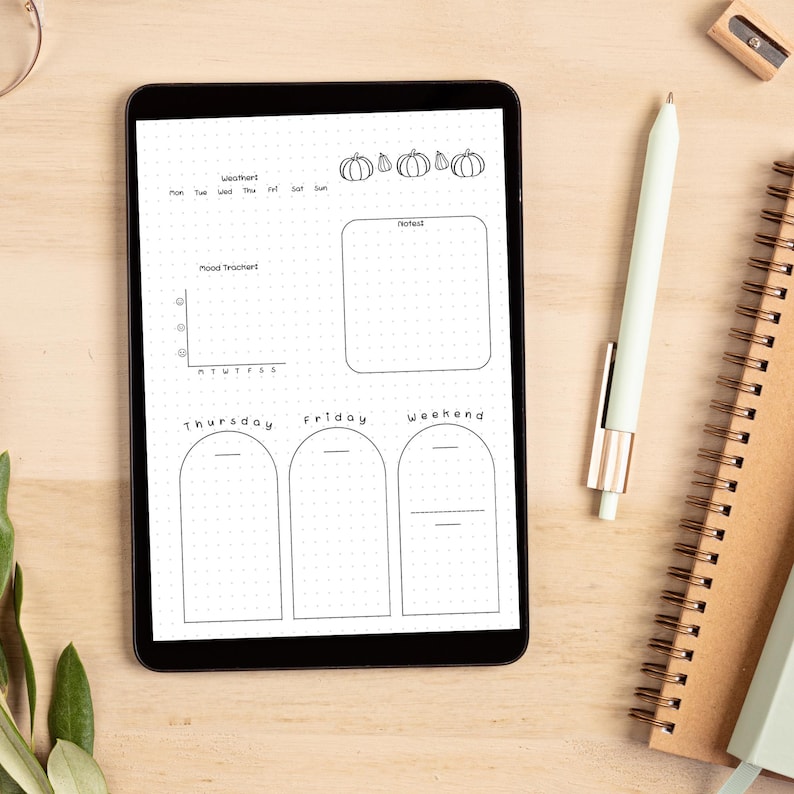 May include: A black and white digital planner with a pumpkin theme. The planner includes sections for weather, mood tracker, notes, and daily tasks. The days of the week are labelled: Monday, Tuesday, Wednesday, Thursday, Friday, Saturday, and Sunday. The planner also includes a section for weekend tasks.