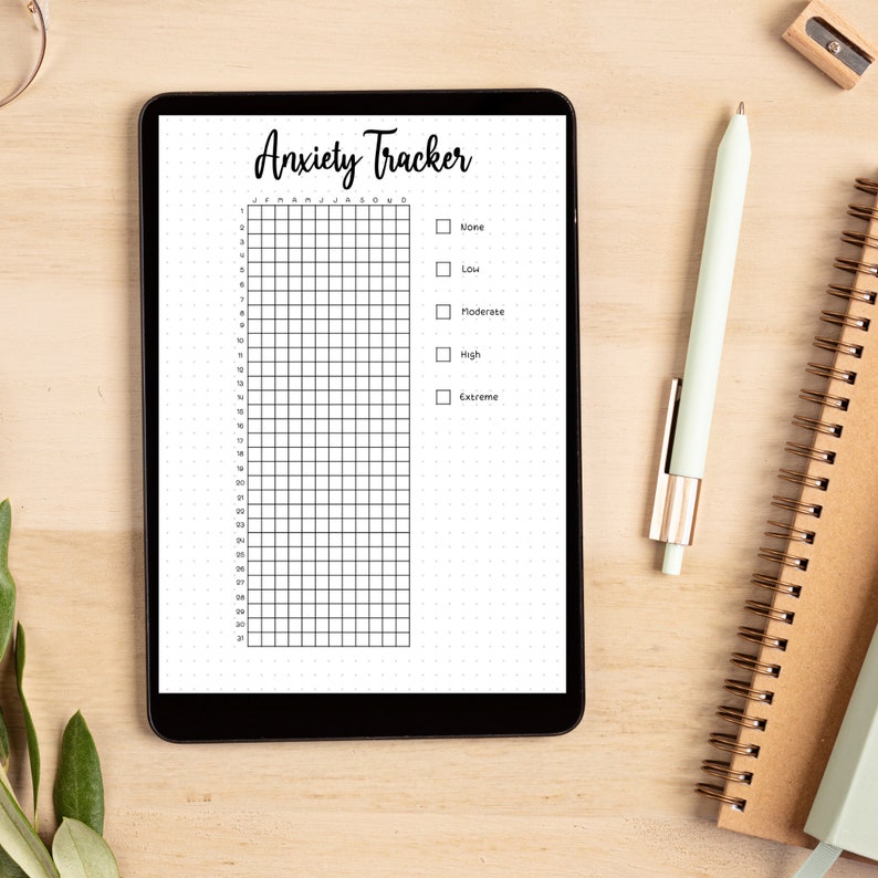 May include: A digital anxiety tracker on a tablet screen. The tracker has a grid with numbers 1-31 and the months of the year. There are checkboxes for rating anxiety levels: None, Low, Moderate, High, and Extreme.