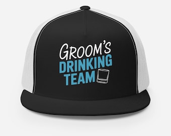 May include: Black and white trucker hat with a white mesh back. The front of the hat has the text "Groom's Drinking Team" in white with a blue glass icon.