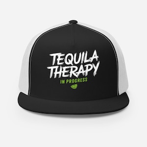 May include: Black and white trucker hat with a white mesh back. The front of the hat has the text "TEQUILA THERAPY IN PROGRESS" in white with a green lime wedge graphic.