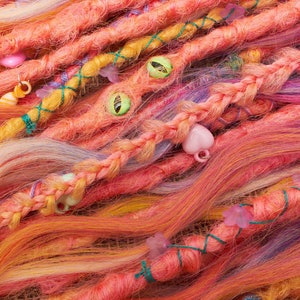 May include: A close-up of a colorful set of synthetic dreadlocks with various beads and charms. The dreadlocks are a mix of pink, orange, yellow, and purple.
