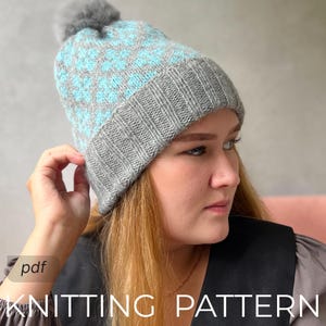 May include: A gray and light blue knitted hat with a pom-pom. The hat features a geometric pattern in light blue and a ribbed gray brim. The text "KNITTING PATTERN" is visible at the bottom of the image.
