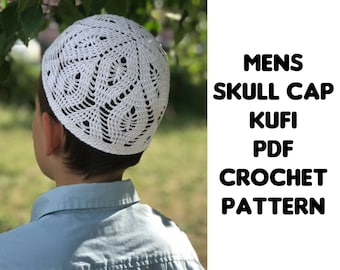 May include: A white, crocheted skull cap with an openwork design. The cap is worn by a person in a light blue shirt. Text on the right side of the image reads: MENS SKULL CAP KUFI PDF CROCHET PATTERN.