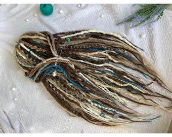 Pode incluir: Um conjunto de dreadlocks sintéticas nas cores marrom, branco e azul turquesa. As dreadlocks são decoradas com contas e pingentes.
