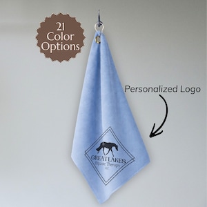 May include: A light blue towel with a personalized logo, hanging from a hook. The logo features a horse silhouette within a diamond shape, with the text "GREAT LAKES Equine Therapy LLC." The image also includes the text "21 Color Options."