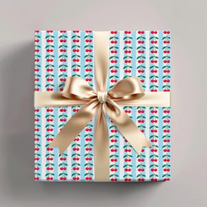 Gift box wrapped in blue cherry-themed paper with red berries and green leaves, tied with a shiny beige ribbon bow, perfect for fun and cheerful gift-giving.