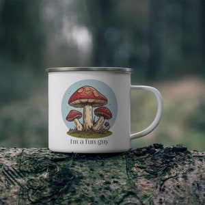May include: White enamel camping mug with a blue circle and a cartoon illustration of three red and white mushrooms. The text "I'm a fun guy" is printed on the mug.