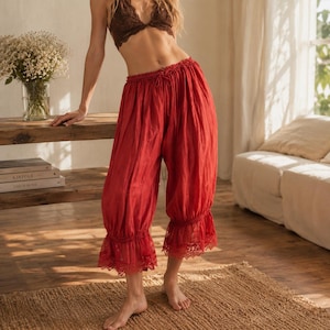Puede incluir: Pantalones rojos de corte holgado con cintura el&aacute;stica fruncida, cord&oacute;n ajustable y ribete de encaje con volantes en el dobladillo. Los pantalones tienen una silueta relajada y voluminosa que cae por debajo de la rodilla, en tela ligera.