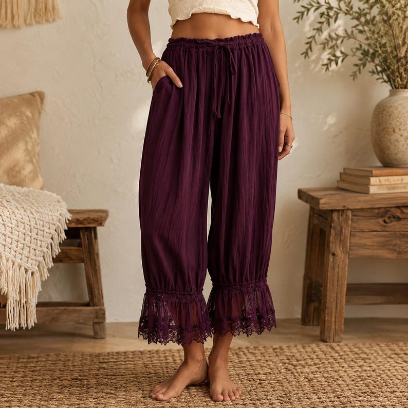 Puede incluir: Pantalones cortos de color morado oscuro con textura arrugada, cintura el&aacute;stica con cord&oacute;n, bolsillos laterales y un borde de encaje ancho y detallado en el dobladillo inferior de cada pernera.