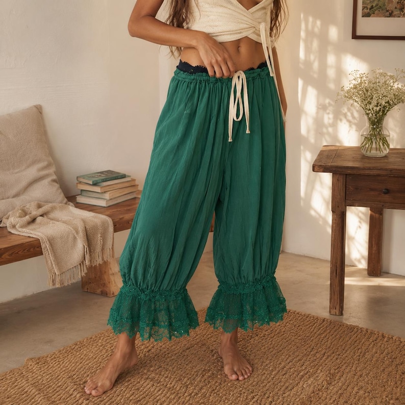 Puede incluir: Pantalones holgados de color verde esmeralda con cintura el&aacute;stica fruncida, cord&oacute;n blanco y ribete de encaje con volantes en el dobladillo. Los pantalones presentan una silueta relajada y voluminosa con un acabado de tela texturizada.