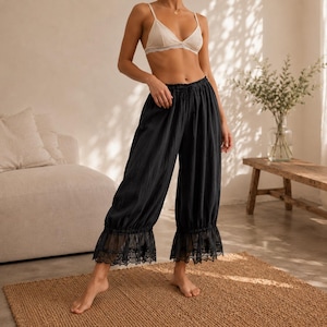 Puede incluir: Pantalones negros de corte holgado con cintura el&aacute;stica fruncida, cord&oacute;n ajustable y un borde ancho de encaje transparente en el dobladillo. Los pantalones tienen una silueta relajada y fluida que llega a media pantorrilla con tela texturizada.