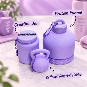 Könnte beinhalten: Ein Set aus hellviolettem Fitnesszubehör, bestehend aus einem Creatine-Gefäß mit schwarzer Aufschrift, einem Protein-Trichter mit strukturiertem Deckel und Kugelkette sowie einem kleinen Tablettenbehälter in Kettlebell-Form in mattem Lila.