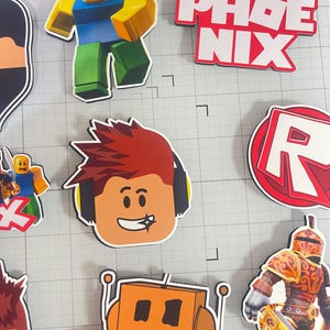 Set of 12 Roblox cupcake toppers featuring popular characters, logos, and icons from the game. Includes layered paper designs with vibrant colors, perfect for gamer-themed birthday parties, cupcakes, and dessert table decor. Ideal for Roblox fans and video game celebrations.